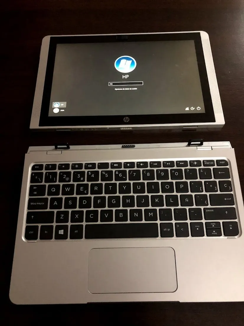 Laptop HP plateado con teclado y pantalla encendida